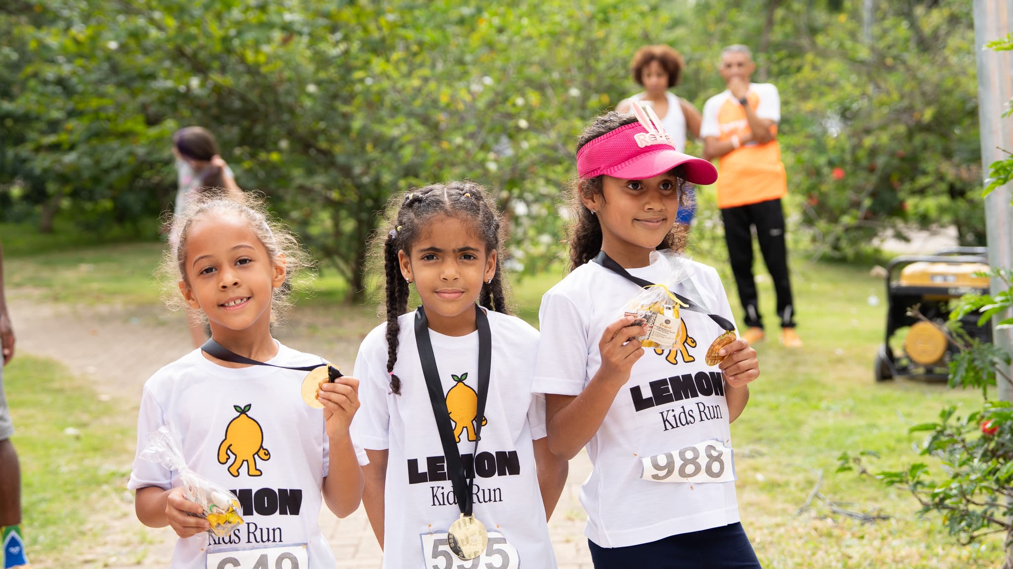 Três meninas sorridentes com medalhas após a corrida