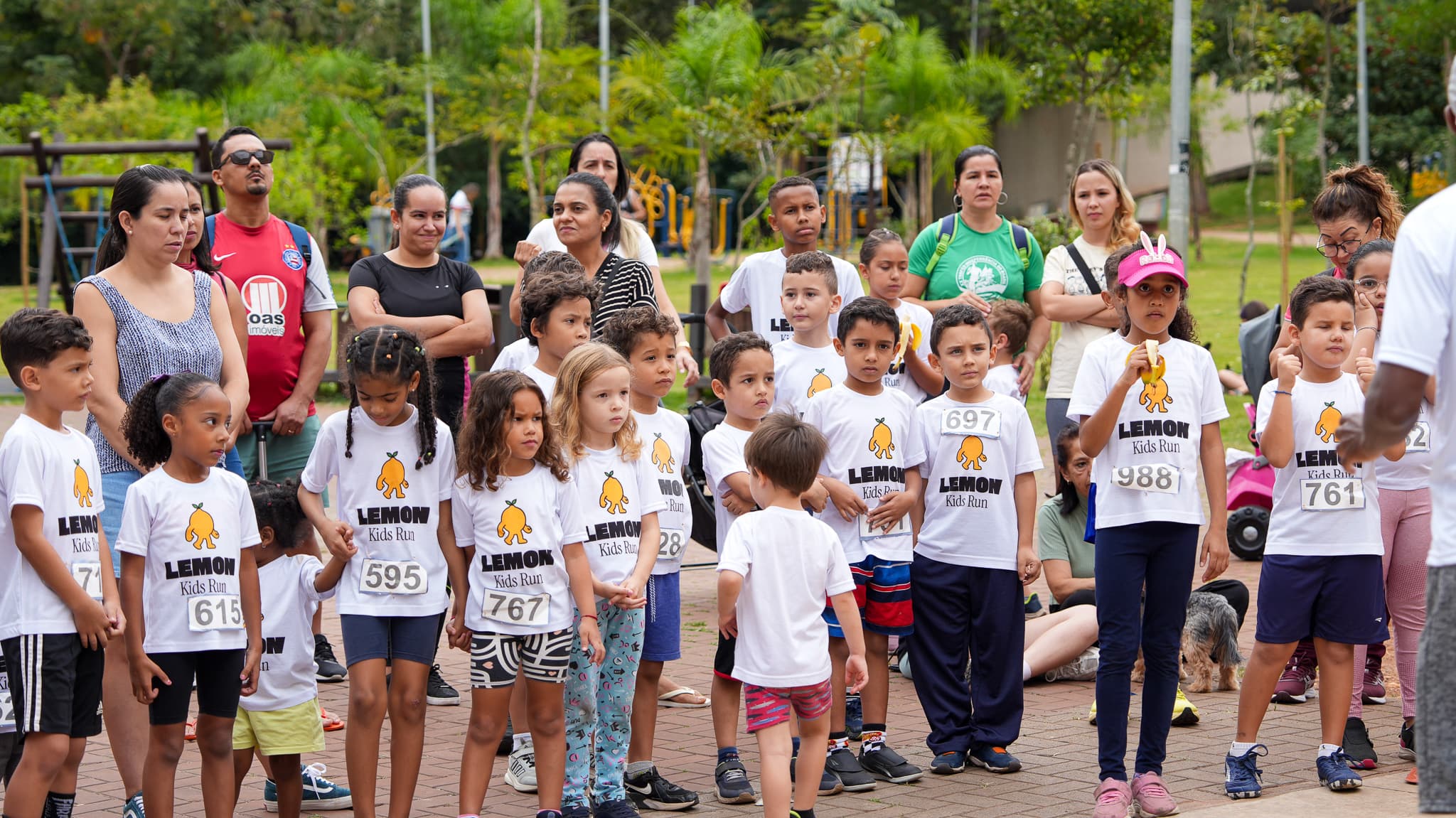 Fila de crianças na largada, com pais e equipe ao fundo